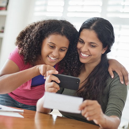 Mother and daughter depositing a check with smartphone